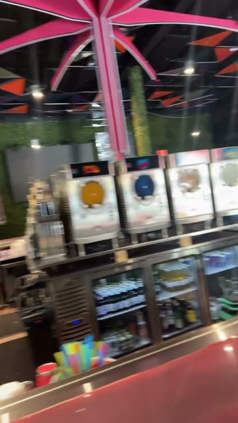 The bar with four frozen-drink machines under a pink starburst ceiling fixture